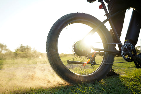 Roue arrière du vélo électrique DYU King 750 sur un chemin de terre poussiéreux Roue arrière du vélo électrique DYU King 750 sur un chemin de terre poussiéreux