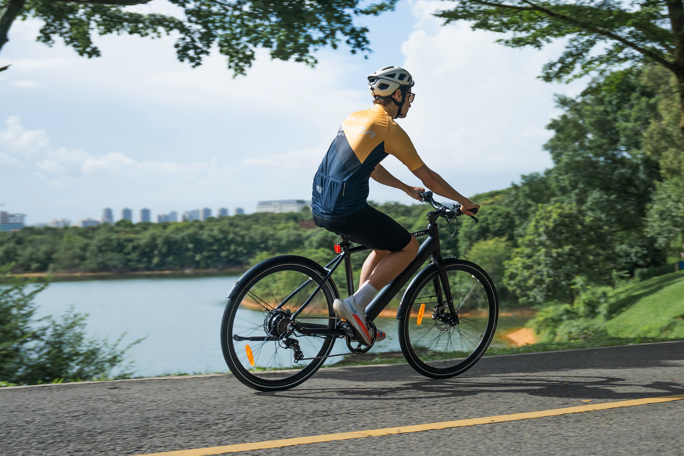 Homme roulant sur un vélo électrique noir près d'un lac dans une zone urbaine. Homme roulant sur un vélo électrique noir près d'un lac dans une zone urbaine.