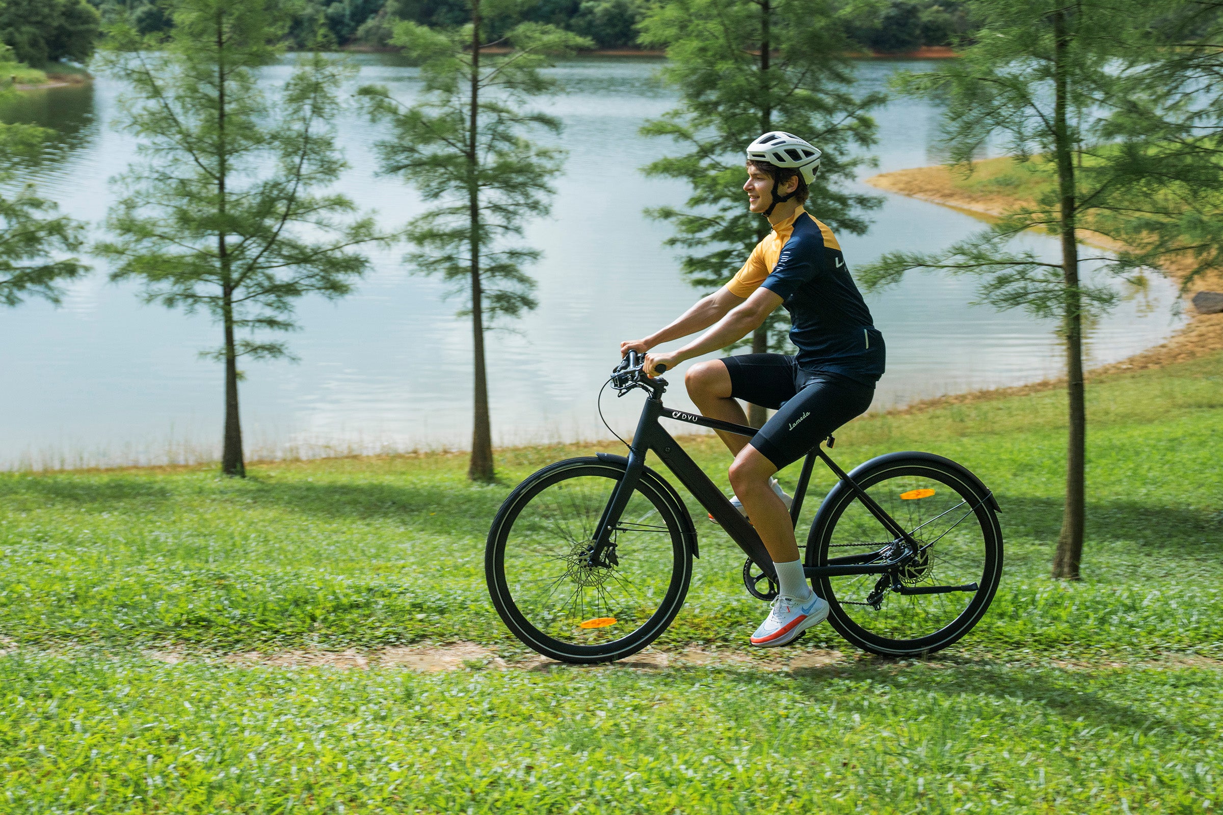 Homme sur un vélo électrique noir dans un parc verdoyant près d'un lac. Homme sur un vélo électrique noir dans un parc verdoyant près d'un lac.