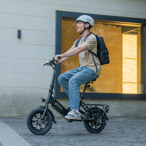 Homme sur vélo électrique pliant DYU C3 noir avec casque en extérieur. Homme sur vélo électrique pliant DYU C3 noir avec casque en extérieur.
