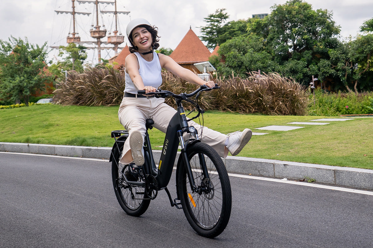 Femme souriante sur vélo électrique DYU C1 noir sur route en plein air. Femme souriante sur vélo électrique DYU C1 noir sur route en plein air.