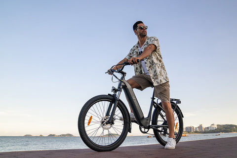 Homme sur vélo électrique DYU C1 noir au bord de la mer avec paysage urbain. Homme sur vélo électrique DYU C1 noir au bord de la mer avec paysage urbain.