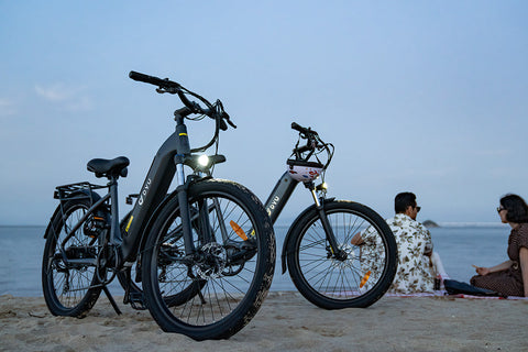 Vélos électriques DYU C1 noir et gris sur la plage, décor relaxant au bord de la mer. Vélos électriques DYU C1 noir et gris sur la plage, décor relaxant au bord de la mer.